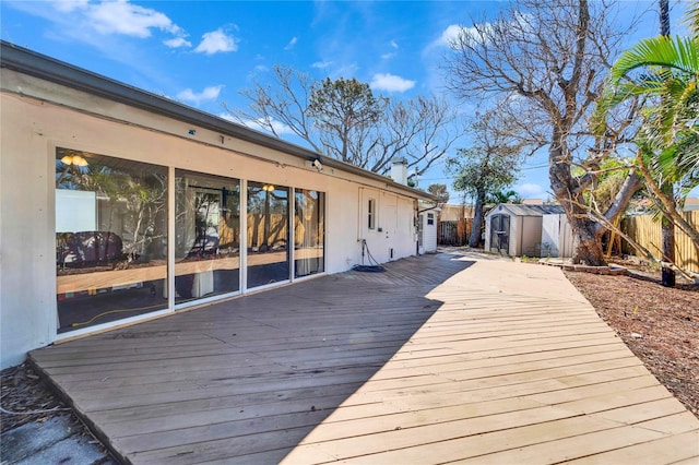 wooden terrace featuring fence, a storage unit, and an outdoor structure