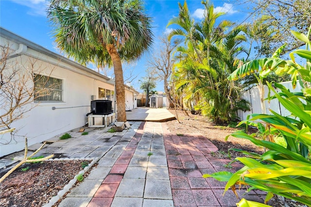 view of patio / terrace with cooling unit, a fenced backyard, an outdoor structure, and a storage shed