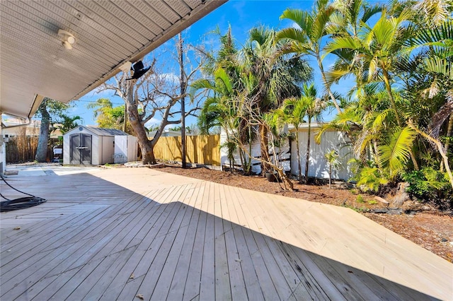 wooden deck featuring an outbuilding, fence, and a storage unit