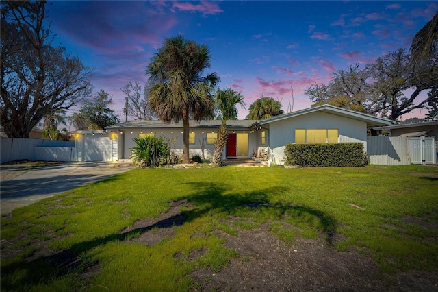 view of front facade with driveway, a front lawn, fence, and stucco siding