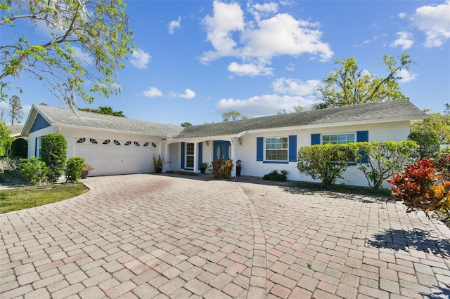 ranch-style house featuring brick siding, decorative driveway, and an attached garage