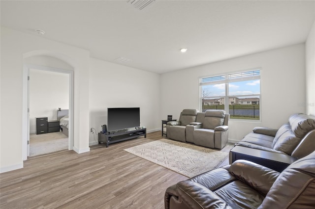 living area with baseboards, visible vents, and light wood-style floors