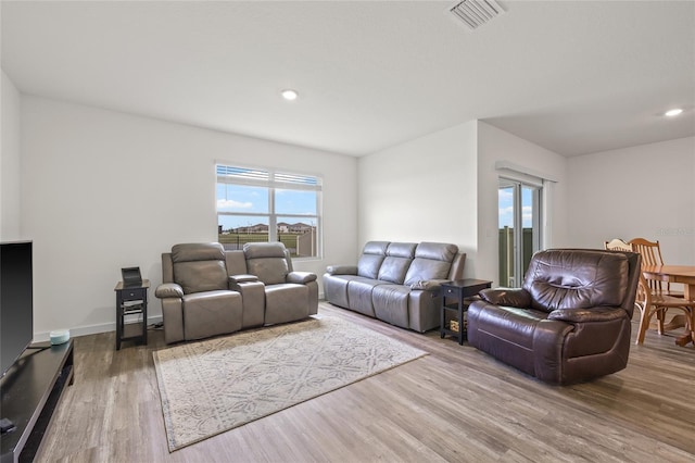 living room with recessed lighting, visible vents, baseboards, and wood finished floors