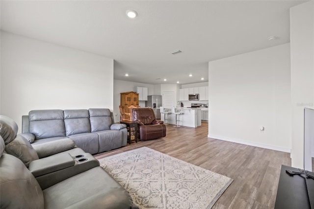 living area featuring baseboards, recessed lighting, visible vents, and light wood-style floors