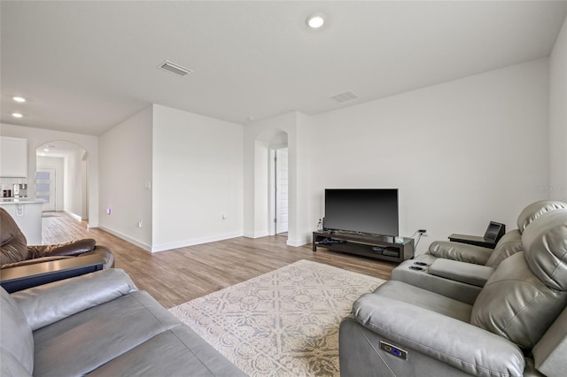 living room featuring visible vents, arched walkways, baseboards, light wood-style flooring, and recessed lighting