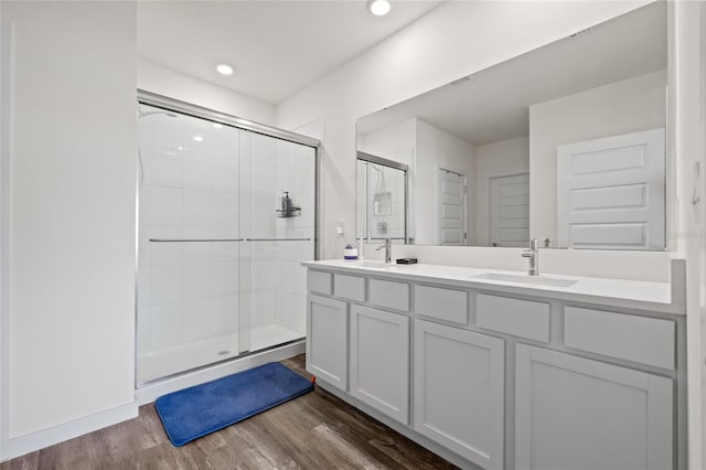 bathroom featuring a sink, a shower stall, and wood finished floors