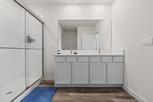 bathroom featuring a sink, a shower stall, baseboards, and wood finished floors