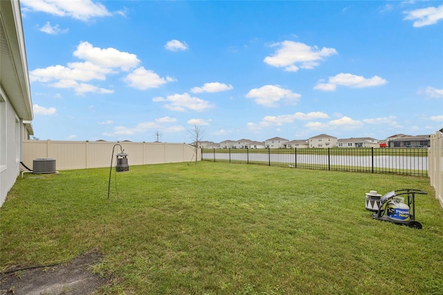 view of yard with central air condition unit, a fenced backyard, and a residential view