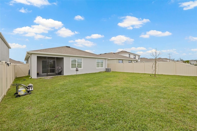 back of property featuring a sunroom, a fenced backyard, a lawn, and stucco siding