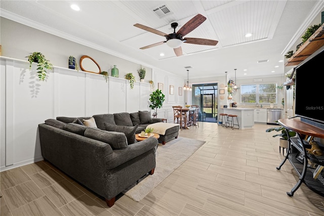 living area featuring crown molding, a ceiling fan, and visible vents