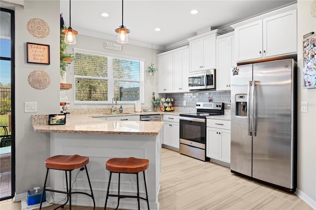 kitchen featuring light stone countertops, a peninsula, appliances with stainless steel finishes, white cabinetry, and tasteful backsplash