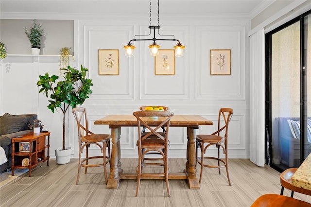 dining area featuring a decorative wall, breakfast area, crown molding, and wood finish floors