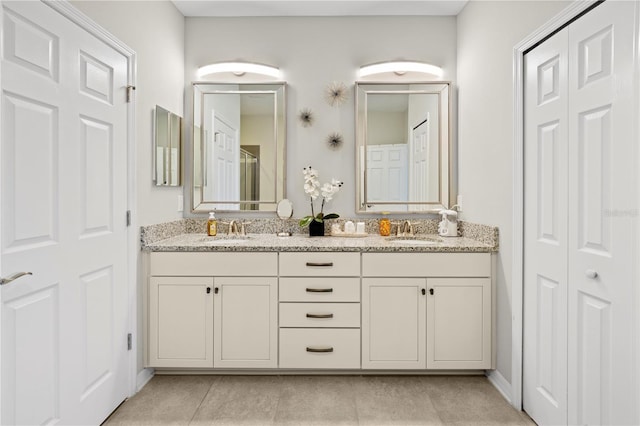 full bath with a sink, double vanity, and tile patterned floors