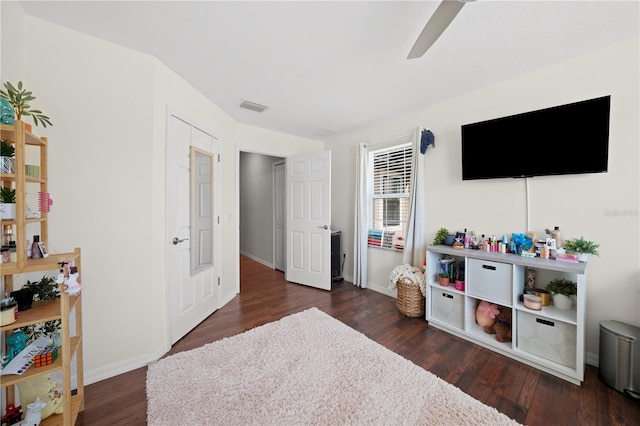 interior space featuring ceiling fan, visible vents, baseboards, and dark wood finished floors