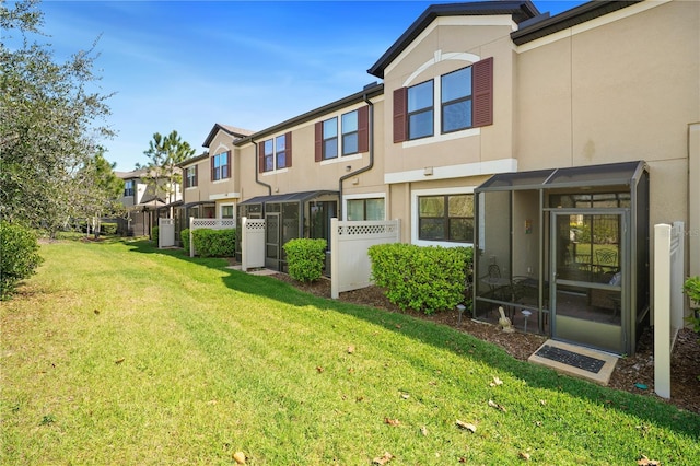 rear view of property with a lawn, fence, a residential view, and stucco siding