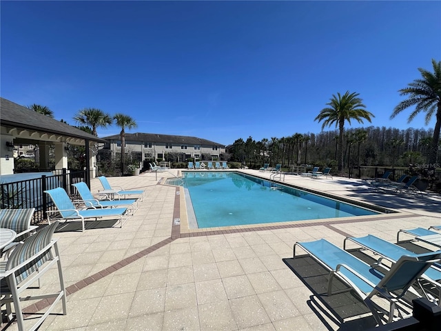 pool with a patio and fence