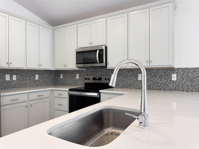 kitchen with appliances with stainless steel finishes, light countertops, backsplash, and white cabinetry