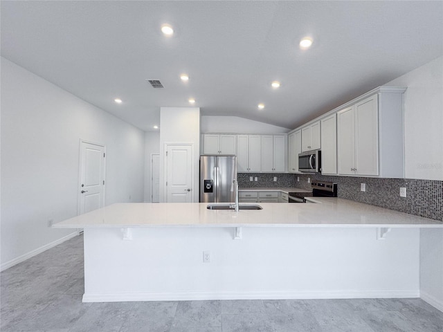 kitchen featuring stainless steel appliances, tasteful backsplash, visible vents, a sink, and a kitchen breakfast bar