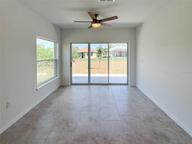 unfurnished room featuring visible vents, plenty of natural light, a ceiling fan, and baseboards