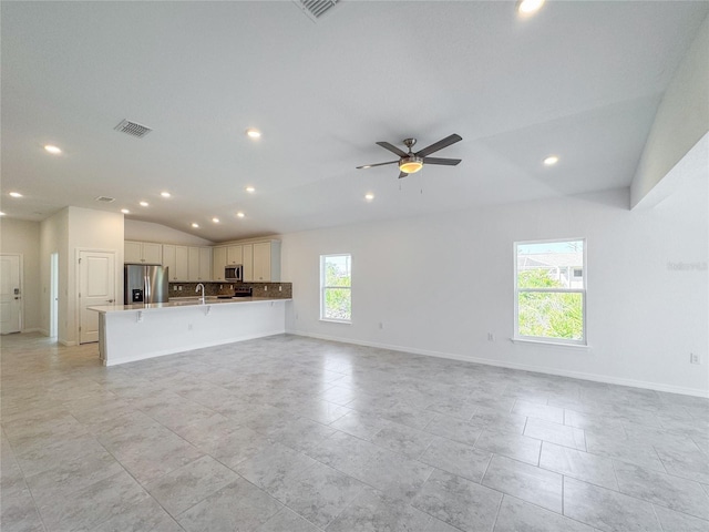 unfurnished living room with baseboards, visible vents, vaulted ceiling, and a ceiling fan