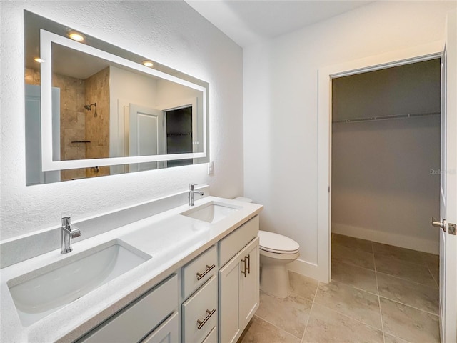 bathroom with toilet, a walk in closet, a sink, and tiled shower