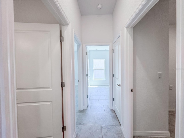 corridor with light tile patterned floors and baseboards