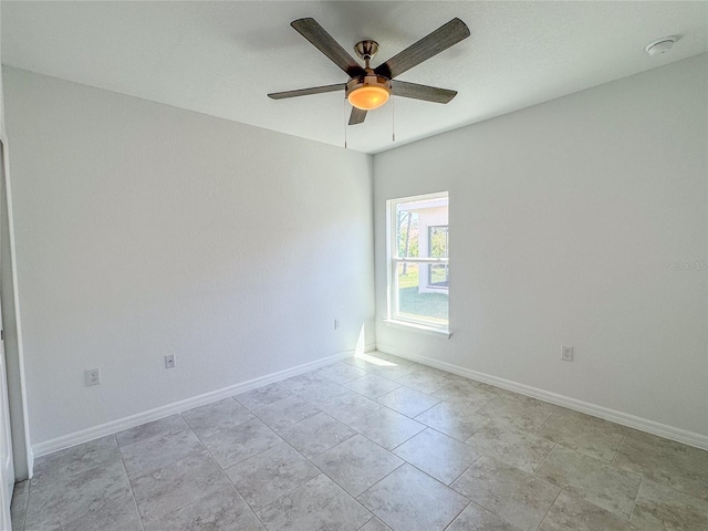 spare room with a ceiling fan and baseboards