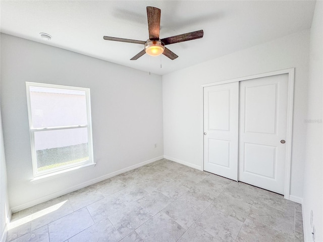 unfurnished bedroom featuring ceiling fan, baseboards, and a closet