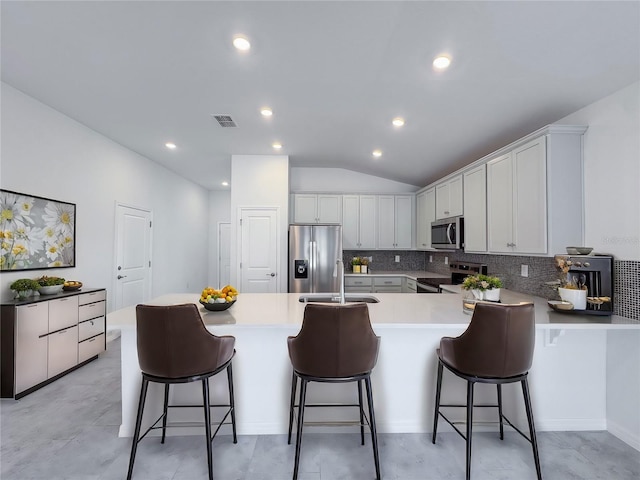 kitchen featuring stainless steel appliances, a peninsula, a sink, visible vents, and backsplash