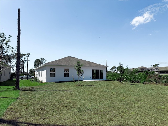 back of property with a lawn and stucco siding