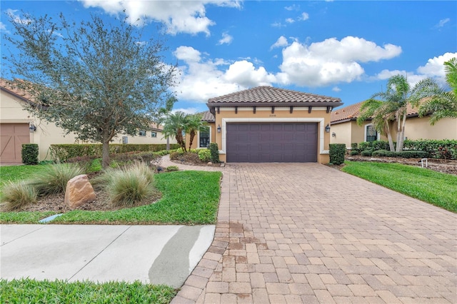 mediterranean / spanish home featuring an attached garage, a tile roof, decorative driveway, and stucco siding