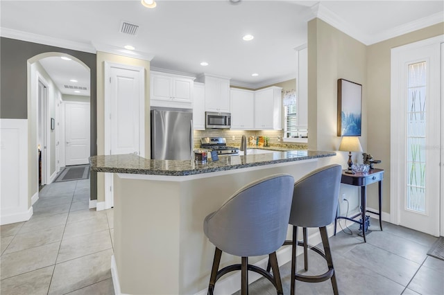 10446 Highland Park Pl, Palmetto, FL 34221 - kitchen featuring appliances with stainless steel finishes, a kitchen breakfast bar, dark stone countertops, healthy amount of natural light, and crown molding