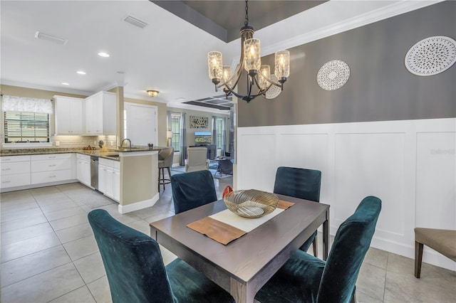 10446 Highland Park Pl, Palmetto, FL 34221 - dining area with a chandelier, light tile patterned flooring, crown molding, a decorative wall, and a wainscoted wall