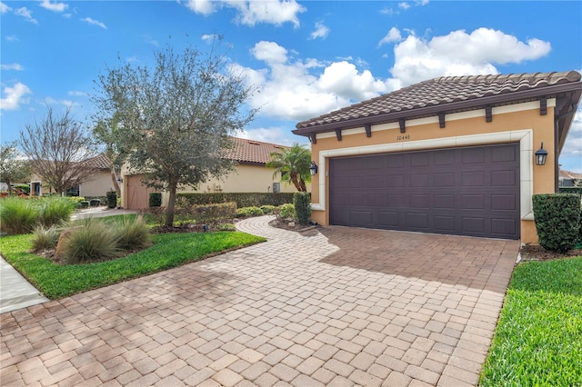 10446 Highland Park Pl, Palmetto, FL 34221 - mediterranean / spanish-style home featuring stucco siding, decorative driveway, a tiled roof, and a garage