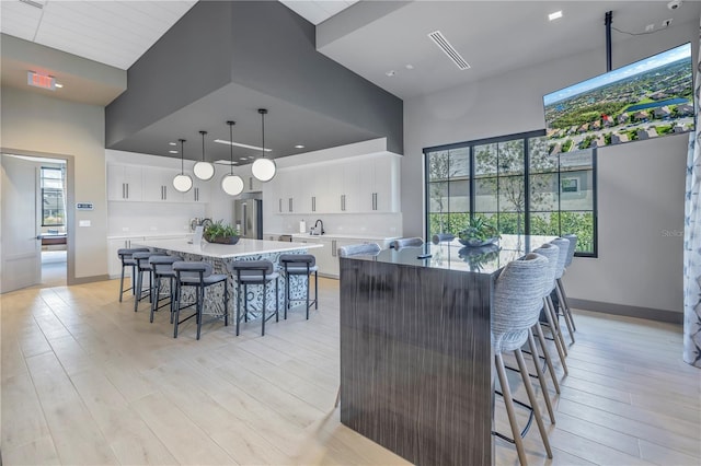 10446 Highland Park Pl, Palmetto, FL 34221 - kitchen with high end fridge, a large island with sink, a breakfast bar, light wood-style floors, and a towering ceiling