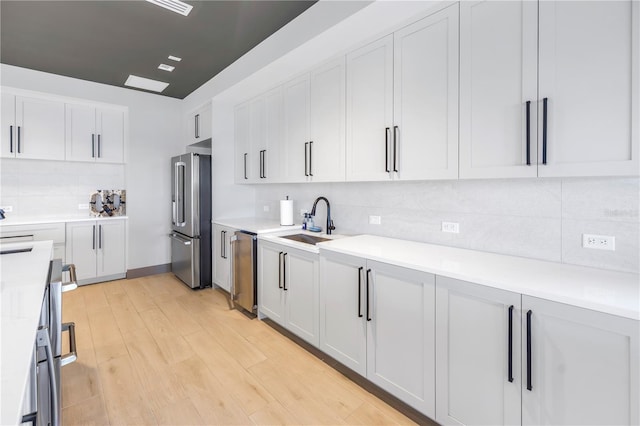10446 Highland Park Pl, Palmetto, FL 34221 - kitchen with stainless steel appliances, a sink, decorative backsplash, light wood finished floors, and light countertops