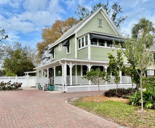 view of front of property with a porch, decorative driveway, and fence