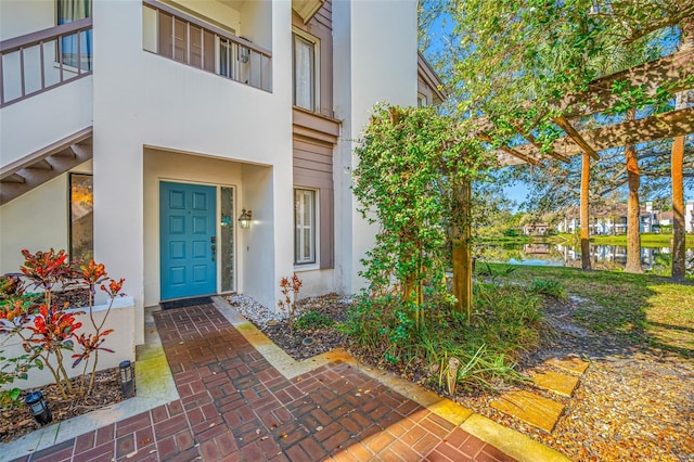 view of exterior entry with a water view and stucco siding