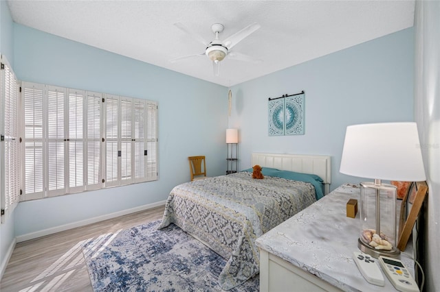 bedroom featuring light wood-style floors, baseboards, and a ceiling fan