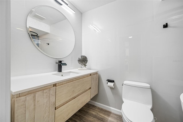 bathroom with toilet, vanity, tile walls, and wood finished floors