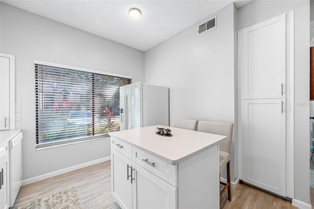 interior space featuring light wood-style floors, white appliances, visible vents, and white cabinetry