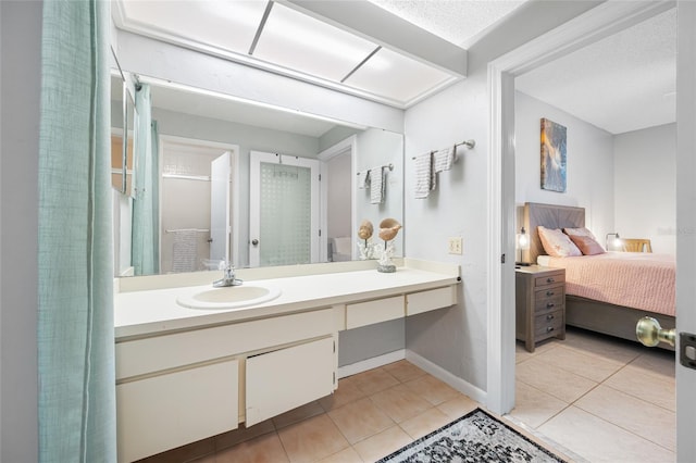 bathroom featuring baseboards, vanity, ensuite bath, and tile patterned floors