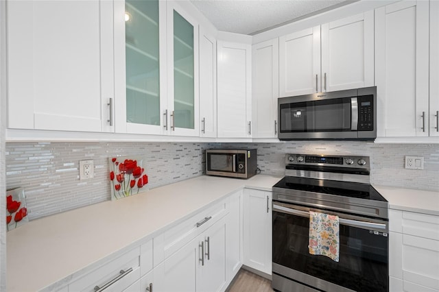 kitchen featuring light countertops, appliances with stainless steel finishes, white cabinetry, and decorative backsplash