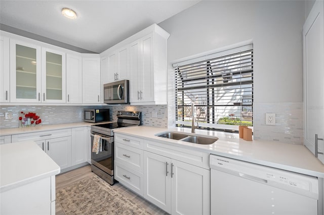 kitchen with appliances with stainless steel finishes, backsplash, a sink, and white cabinetry