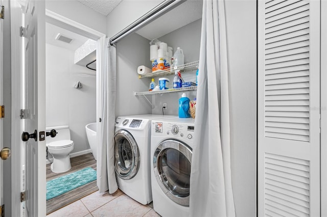 clothes washing area featuring light tile patterned floors, laundry area, visible vents, and washer and dryer