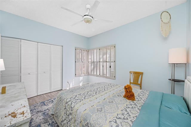 bedroom with a textured ceiling, a closet, wood finished floors, and a ceiling fan