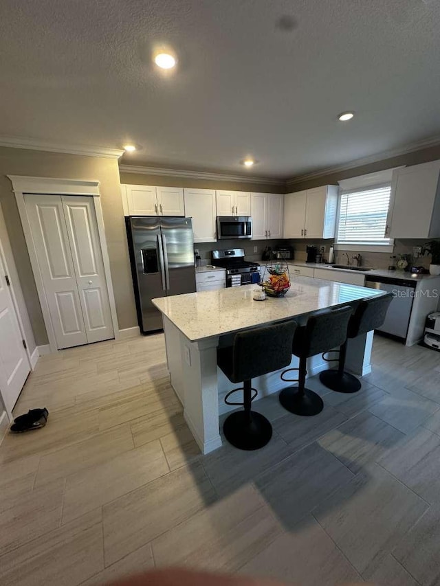 kitchen featuring white cabinets, appliances with stainless steel finishes, a center island, and a breakfast bar area