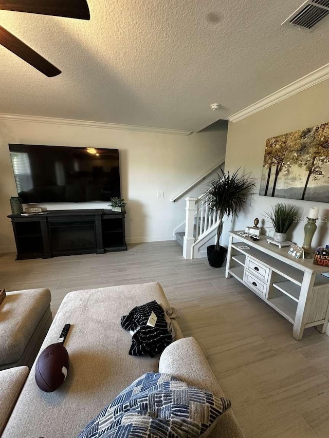 living room with visible vents, wood finish floors, stairs, a textured ceiling, and crown molding