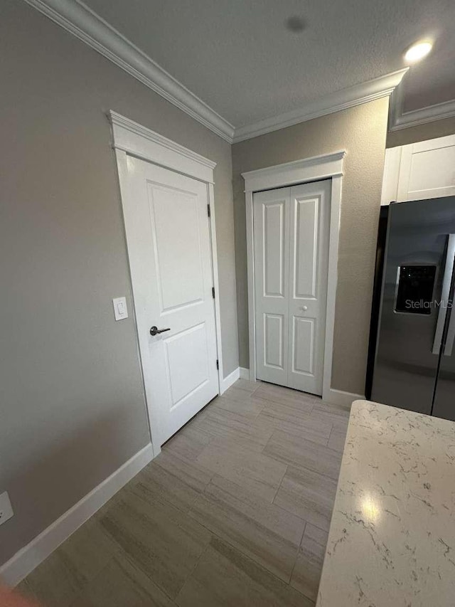 hall with light wood-style floors, baseboards, and ornamental molding