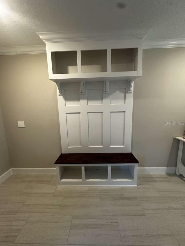 mudroom featuring a textured ceiling, baseboards, and ornamental molding